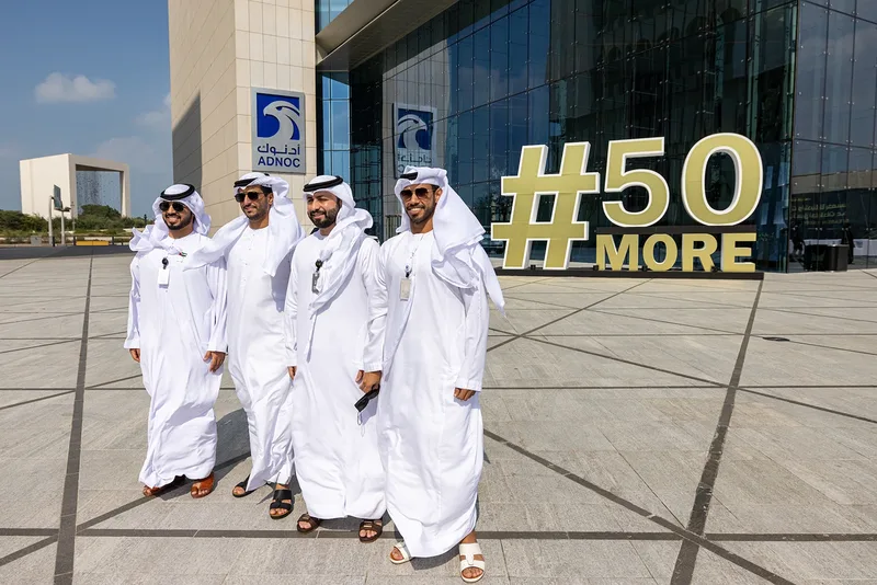 ADNOC employees beside the #50More anniversary installation during the Jubilee celebration