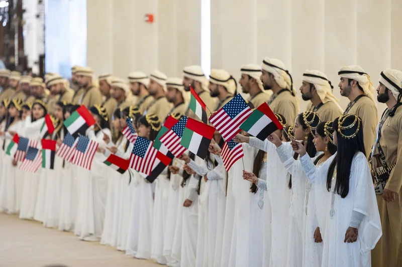 Emirati performers and children welcoming guests with UAE and US flags at the USA Presidential Reception in Abu Dhabi